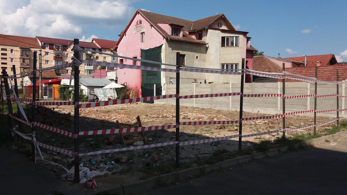 Lebontott ház helyén szabaddá tett telek kordonszalaggal elkerítve, háttérben szomszédos épületek